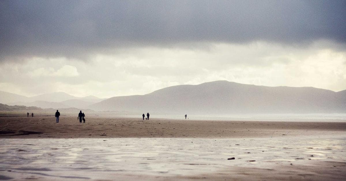 Newcomer holding apartment keys and a rental agreement, standing safely in front of a Canadian building.